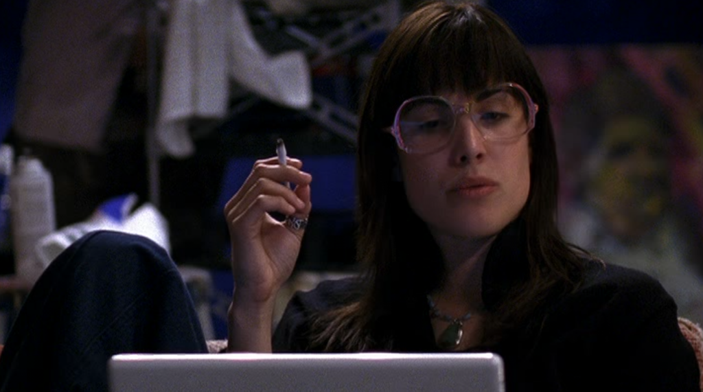 Shulamith looking at her computer,, smoking (played by Carly Pope)